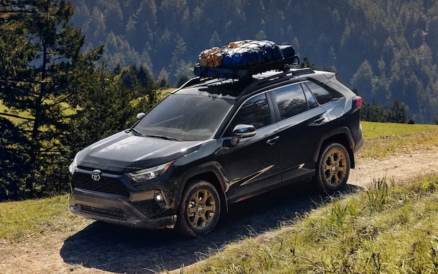 A black 2025 RAV4 drives along a mountain road.